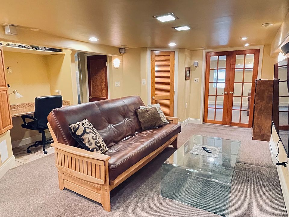 Fully furnished living room with wall-mounted TV, large storage closet, fold-out futon, built in desk, very well lit.