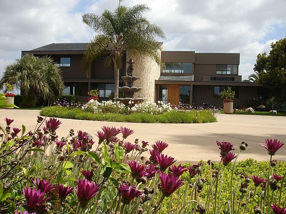 Grand frontage w/ fountain, palm trees & flowers galore.