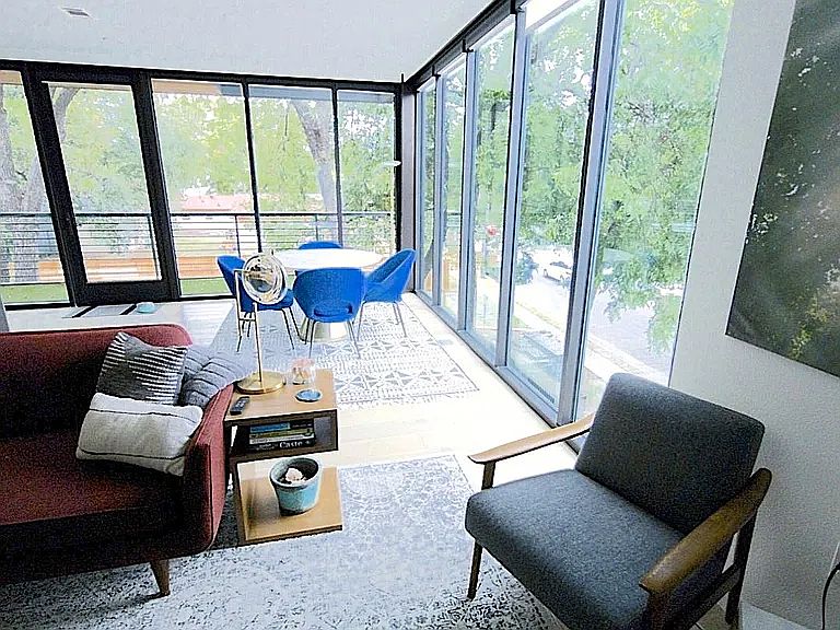 Stunning open-concept living room with two walls of windows, abundant natural light, and sleek automated blinds.