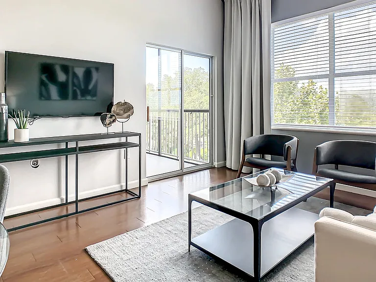 Delight in the timeless elegance of your airy living room inviting natural light indoors through large windows and sliding patio doors leading to your private balcony or patio.