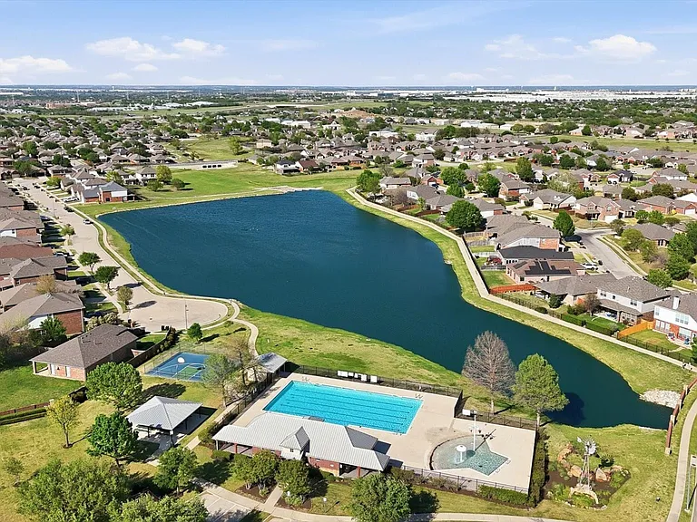 Neighborhood aerial featuring a central lake, a community swimming pool, and a tennis court