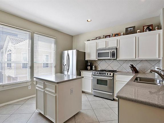 Large island kitchen fills with natural light. Custom cabinets and stainless steel appliances.