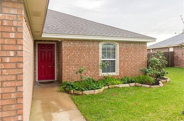 Red door entry accents the beautiful curb appeal to this cozy home.