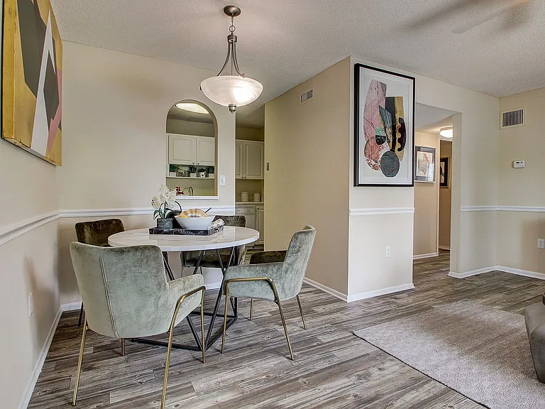 Bright and inviting dining area with modern velvet chairs, round table, and contemporary artwork for a stylish touch.