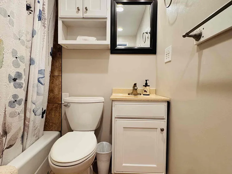 Shared tiled bathroom and tile flooring, ceiling fan, toilet, sink and storage space for items