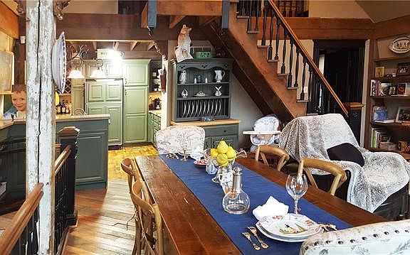 Great Room opens to kitchen.  Built in bookshelves and steps to loft from reclaimed lumber and antique millwork.