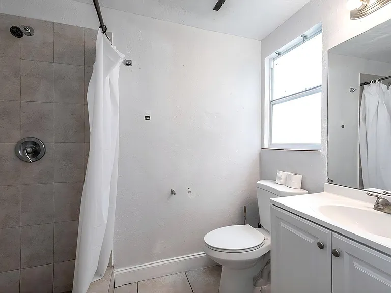 Full bathroom with tiled walk-in shower, single-sink vanity, and a window for everyday ventilation and natural light.