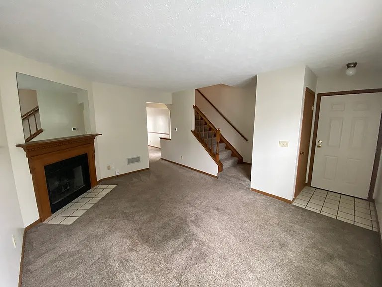 Front living room; ornamental fireplace, stair to second floor and front door.