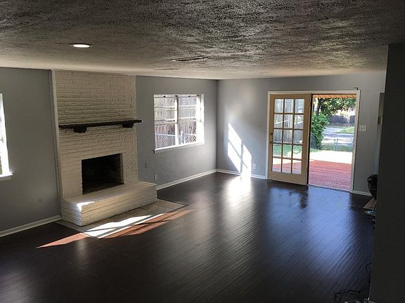 Large living room with wood floors, fireplace and doors to t