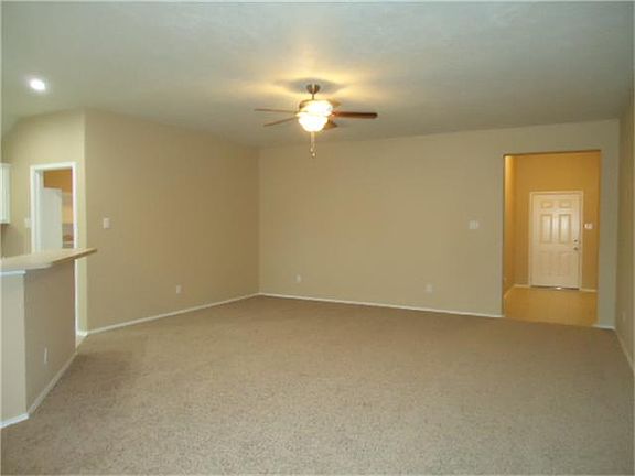 Spacious living room with new ceiling fan, paint and carpet.