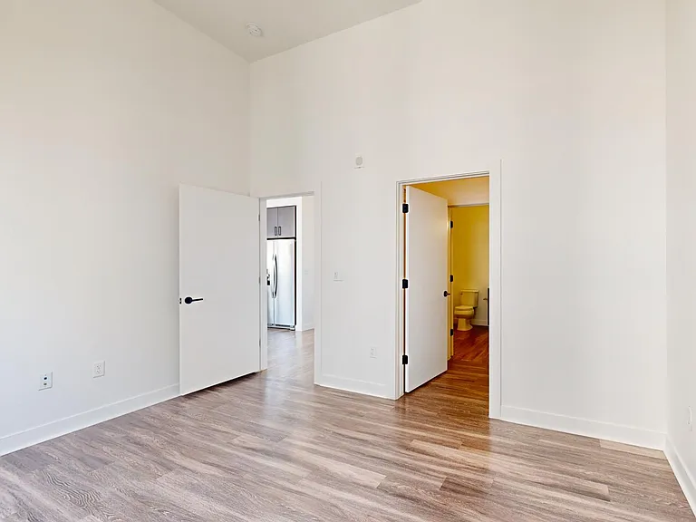 Spacious apartment bedroom with large closet, attached bathroom, and wood-style flooring.