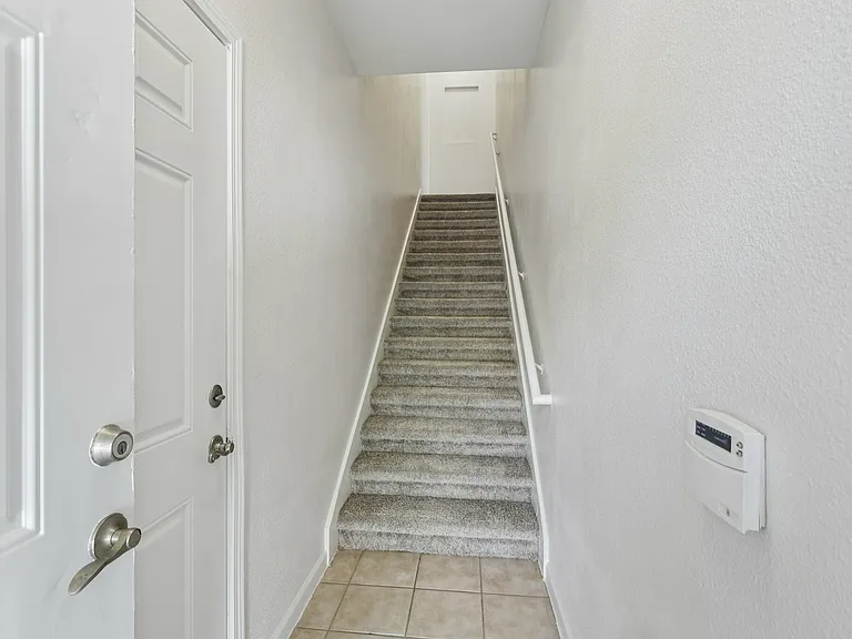 Inviting entryway featuring a modern staircase with soft carpet and clean white walls, offering a stylish and welcoming home entrance. Inviting entryway featuring a modern staircase with soft carpet and clean white walls, offering a stylish and welcoming 