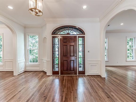 Grand foyer with wainscoted walls and arched entry ways into the living areas and dining room. Art niche is tucked adjacent to the front door giving a wonderful view from the dining room.