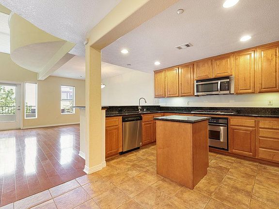 The spacious kitchen boasts stainless steel appliances (convection oven, 5 burner gas stove, microwave, side-by-side refrigerator) granite counters, kitchen island, tiled flooring, and ample pantry space. Perfect kitchen for entertaining friends and famil