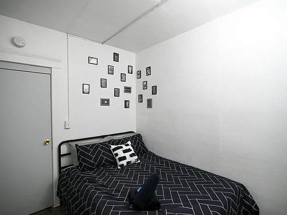 Furnished bedroom with a full-size bed, neutral walls, and space for personal touches with wall art.