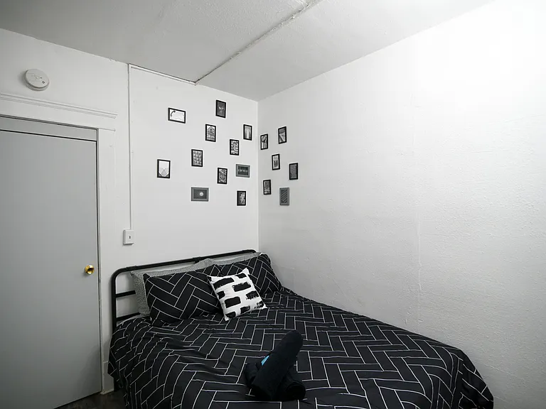 Furnished bedroom with a full-size bed, neutral walls, and space for personal touches with wall art.