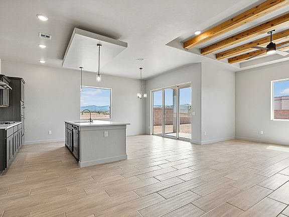 Modern open-concept kitchen and living area with light tile flooring, exposed wooden ceiling beams,
