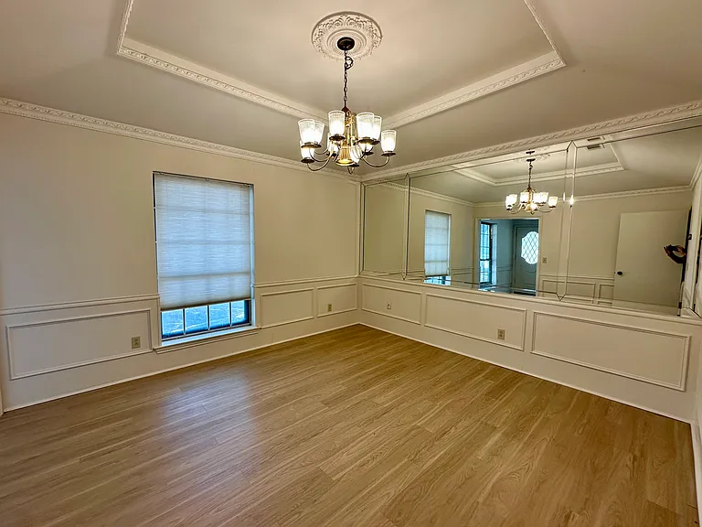Front formal dining area featuring ornamental molding, light wood-style flooring, a tray ceiling, and a nice chandelier. Can be used as an optional office.