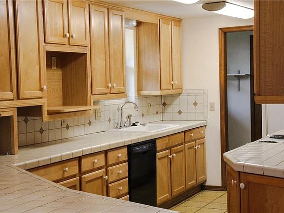 Kitchen with tons of natural wood cabinets, ceramic tile back splash and beautiful stamped concrete floor.