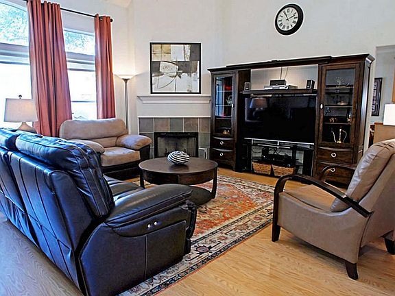 Living room with high ceiling, tall windows, laminate flooring, overlooking beautifully landscaped d