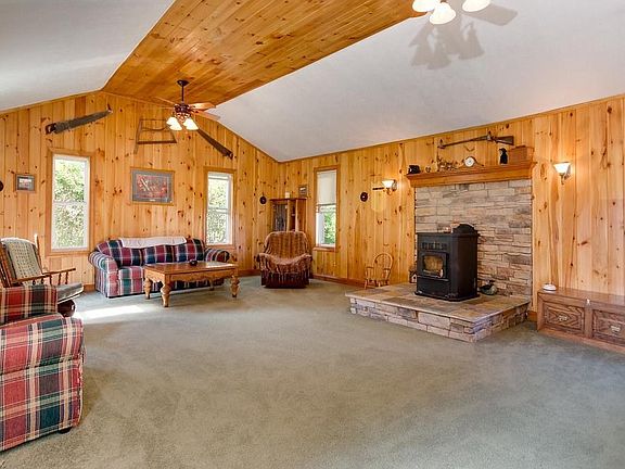 great room with pellet stove, natural cedar paneling, vaulted ceilings, ceiling fans and plenty of windows for natural light