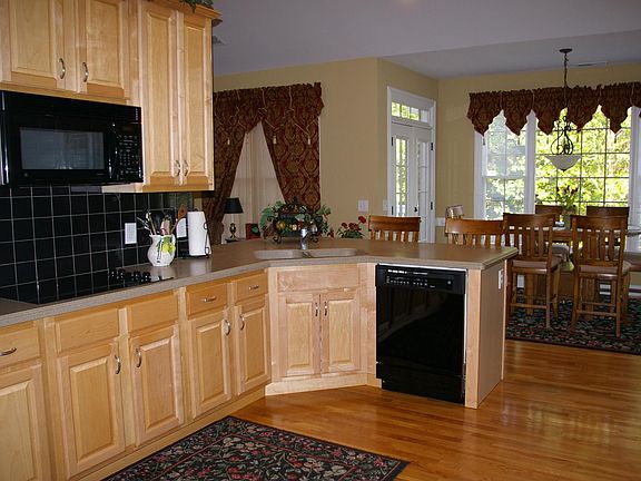 Hardwoods, custom cabinets, Corian, double oven, smooth cooktop, and bar.