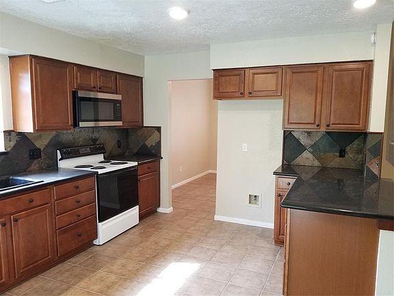 Kitchen with granite counters and tile backsplash. New stainless microwave. Water hookup for refrigerator icemaker. Lots of cabinet space and a pantry. Door leads to dining room for easy access.
