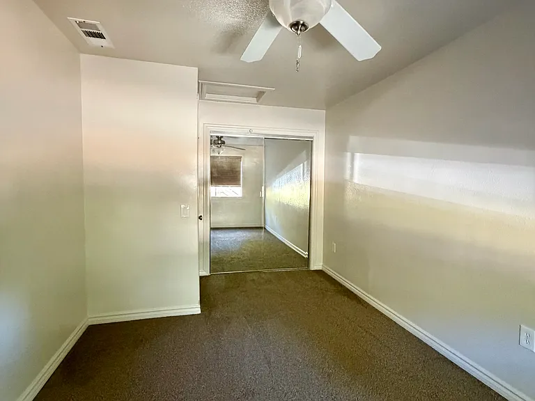 Bedroom #2 with mirrored closet, ceiling fan, and blackout shades