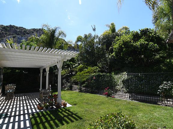 Backyard faces a slope. The houses at the top of the slopes are hidden by thick thick bushes and shrubs.