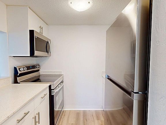 Modern kitchen with sleek stainless steel appliances, pristine white cabinetry, and elegant countertops.