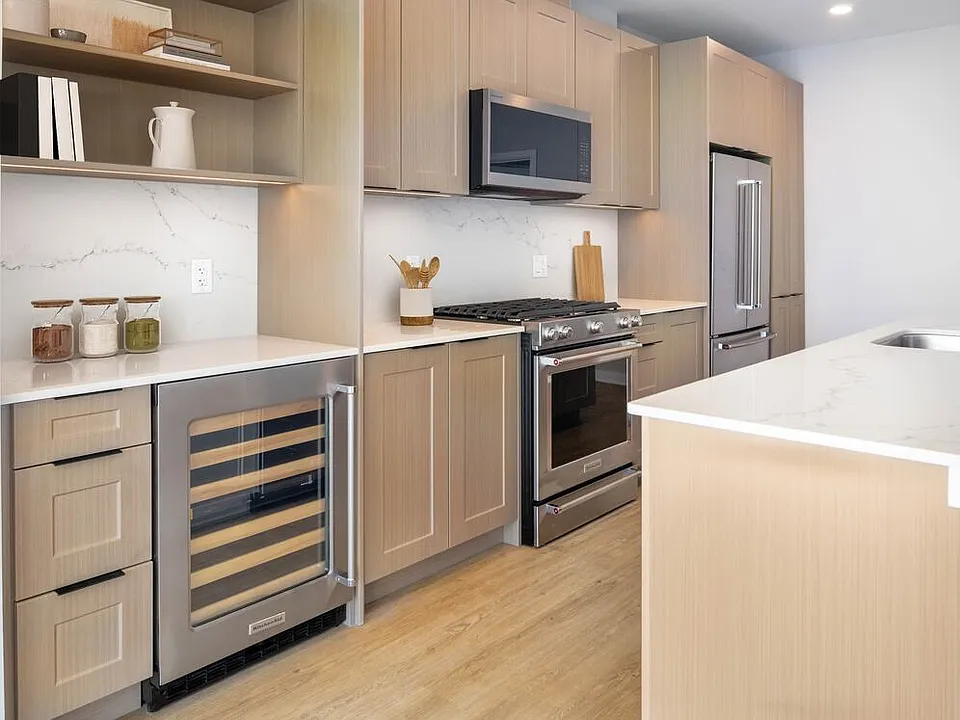 Signature Collection kitchen with oak shaker cabinetry, marbled white quartz countertop, and upgraded stainless steel appliances