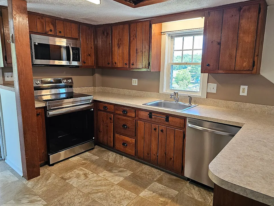 L-shaped kitchen with new appliances and lighting fixtures.