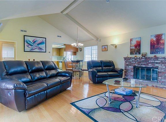 Great room showing lovely large fireplace and beautiful wood flooring.  Dining area and kitchen in background