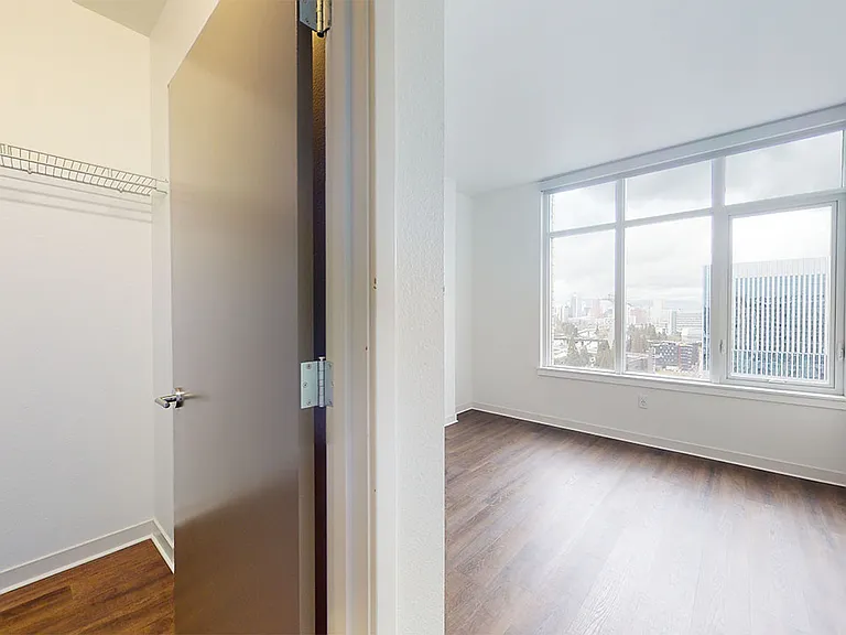 Spacious apartment bedroom with large closet and wood-style flooring.