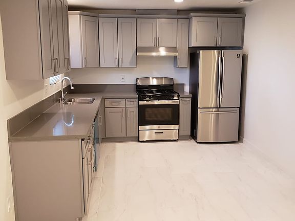 Modern kitchen with new appliances, tiled floor throughout.