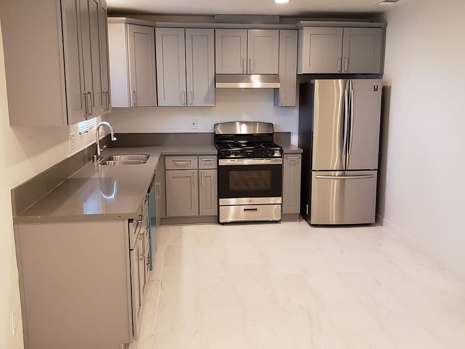 Modern kitchen with new appliances, tiled floor throughout.