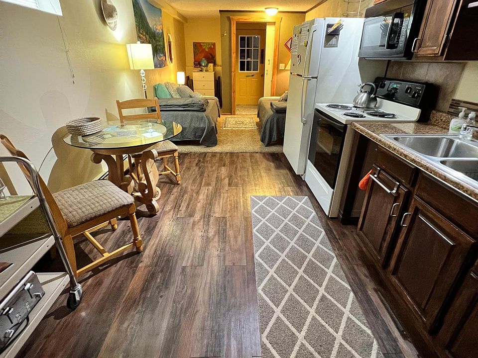 Kitchen view from main bedroom. French doors separate bedroom from kitchen area. Dining table and utility cart are furnished.