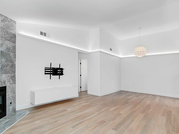 Living room, floating entertainment console, heavy duty TV mount, fireplace with black fireglass, Flower lighting feature in dining room, cove lighting