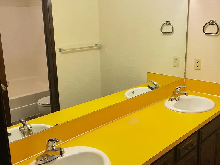 Double sinks in bathroom with pocket door behind sinks leads to private shower/tub and newer toilet.