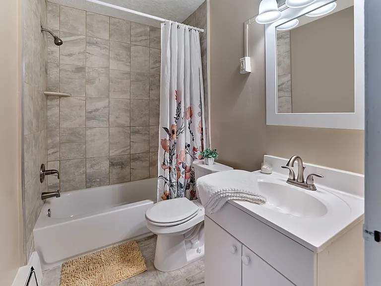 Freshly updated bathroom featuring tile shower surround and modern finishes at Audubon Arms Apartments