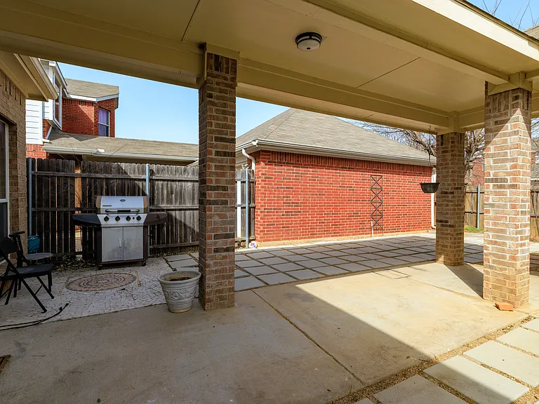 Patio with chairs and grill, partially covered.