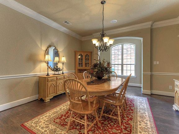 The beautiful formal dining area offers a picture-perfect setting for holiday meals, executive entertaining, or large family gatherings. Rich hardwood flooring, arched entryway, chandelier, crown millwork, & chair rail enhance this lovely setting