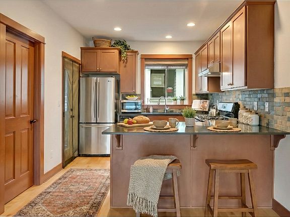 Bright kitchen with granite countertops, stainless steel appliances, and a convenient breakfast bar for casual dining and connection. Don't miss the powder room and balcony.
