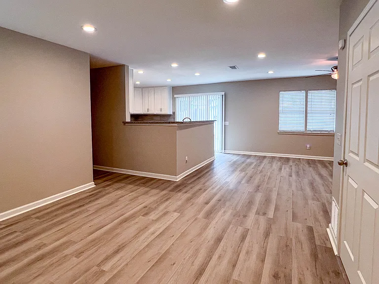 A warm first impression with an open layout, wood-look flooring, and a clear view into the kitchen and main living area.