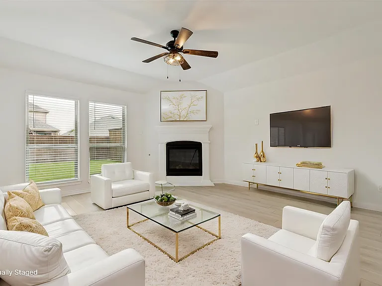Living area featuring a corner fireplace with a white mantel, light wood-finish flooring, and a ceiling fan