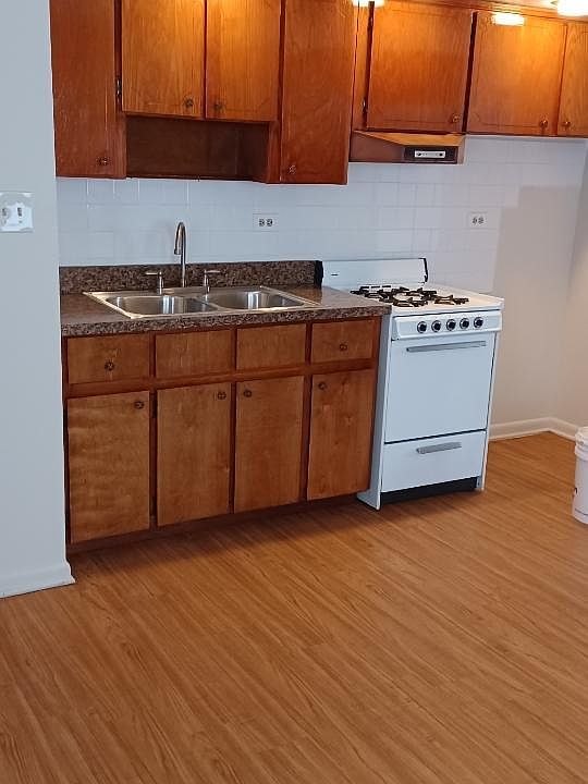Large bright kitchen with modern ceiling lights over working area. Wood look floor.