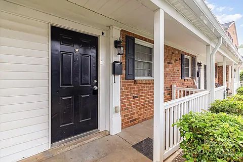 Welcoming Porch Entrance!
Discover comfort and curb appeal in this inviting residential unit. The entrance is framed by a covered porch with white railings and columns.