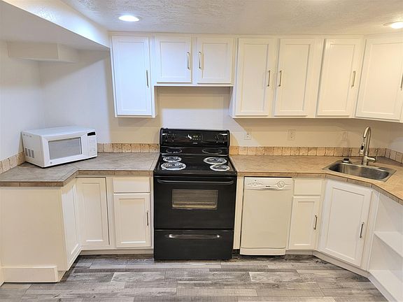 Kitchen has newly refinished cabinet's, new paint, new luxury vinyl flooring, custom tile countertops, and custom overflow shelving. Includes refrigerator, electric stove, dishwasher and microwave. It also includes built in carpeted seating. One window is