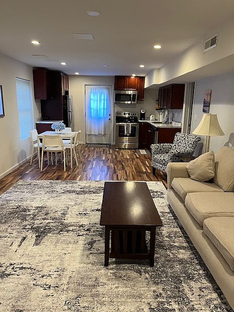 Open Living Room and Kitchen with Dining Area. Kitchen is stocked with plates, glasses, utensils and cookware.