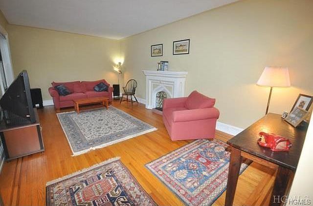The large living room has a decorative fireplace mantel and refinished hardwood floors. The room is 